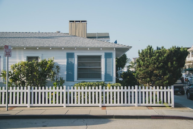 Exterior of a small white home with blue shutters
